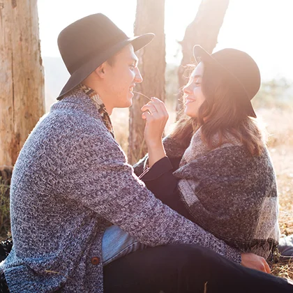 A man and woman sit on a blanket in the woods, enjoying each other's company as best friends amidst nature's beauty.