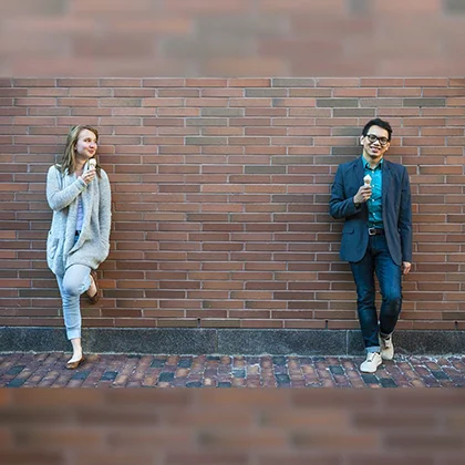 A man and a woman stand beside a brick wall, demonstrating mutual respect for each other's space and individuality.