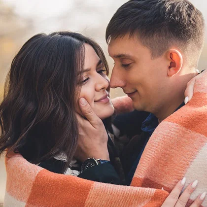 A man and woman share a warm blanket, symbolizing understanding and empathy in their relationship.