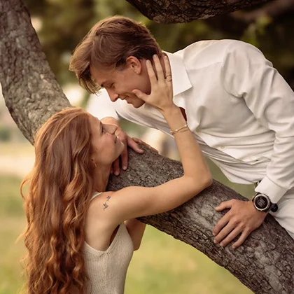 A man and woman lean against a tree, embodying a moment of connection and joy in their relationship.