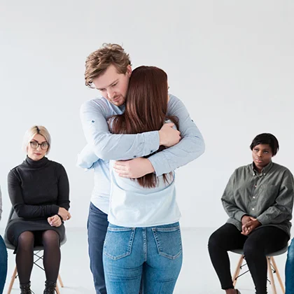 A man embraces a woman in a crowded room, symbolizing support and the strengthening of their bond through mutual trust.