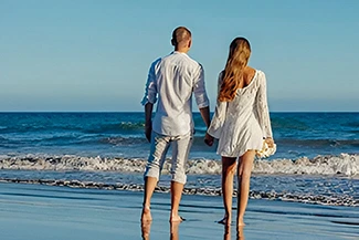 A couple walks hand in hand on the beach, symbolizing their deep friendship and connection in a tranquil environment.