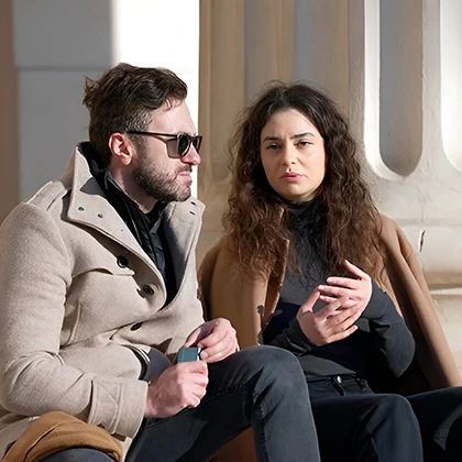 A man and woman sit on a bench, engaged in attentive conversation, listening to each other without interruption.