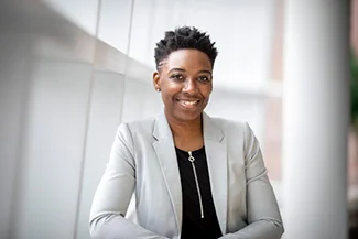 A confident woman in a suit and black shirt sits on a bench, embodying self-belief and the potential for new opportunities.