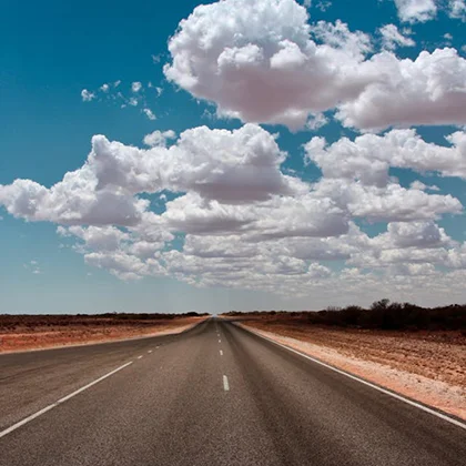 A serene empty road stretches ahead under a sky filled with fluffy clouds, symbolizing limitless possibilities.