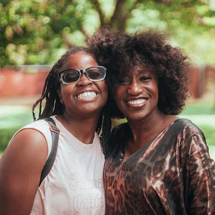 Two women smiling joyfully at the camera, embodying positivity and the beauty of shared moments together.