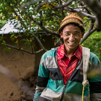 A cheerful man poses in front of a tree, radiating positivity and the infectious power of a smile.