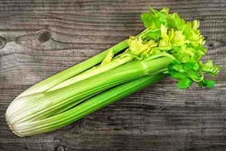 Crisp, fresh celery displayed on a wooden table, emphasizing its vibrant green color and healthy appeal.