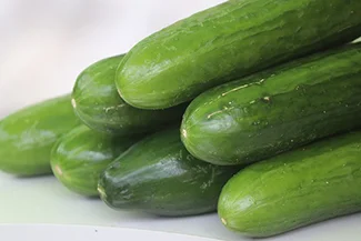 A neatly arranged pile of fresh green cucumbers resting on a clean white surface, showcasing their vibrant color and texture.