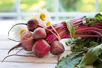 A colorful assortment of fresh beets and cheerful daisies elegantly arranged on a rustic table, highlighting their charm.