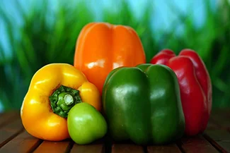 A collection of bright, colorful peppers displayed on a wooden table, highlighting their diverse shapes and vivid colors.