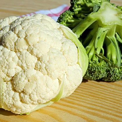 A whole cauliflower placed on a rustic table, highlighting its unique texture and natural color.