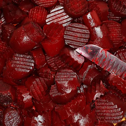 A knife rests centrally atop a vibrant pile of freshly harvested red beets, showcasing their rich color and texture