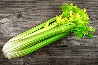 Crisp, fresh celery displayed on a wooden table, emphasizing its vibrant green color and healthy appeal.