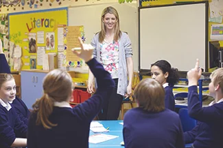 A dedicated woman teaches a group of engaged children in a classroom, highlighting the vital role of women in education.