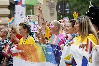 A vibrant assembly of people displaying rainbow flags, symbolizing solidarity and the leadership of women in community projects.