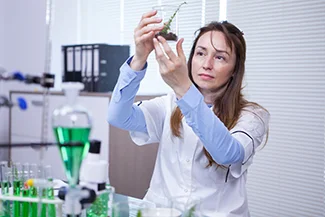 A woman in a lab coat examines a plant, highlighting her meticulous nature and dedication to scientific research.