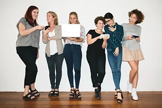 A group of women stands confidently in front of a white wall, symbolizing strong professional and social networks.