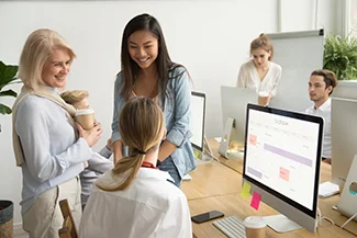 A group of employees engaged in discussion in an office environment, showcasing the impact of women's participation in the economy.