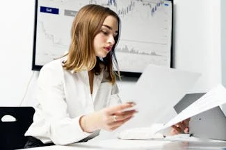 A woman seated at a desk, surrounded by papers and a laptop, representing women's significant role in the global workforce.