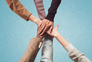 A diverse group of women holding hands, symbolizing teamwork and collaboration in a supportive environment.