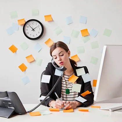 A woman at her desk, surrounded by colorful sticky notes, exemplifying multitasking and organizational skills.