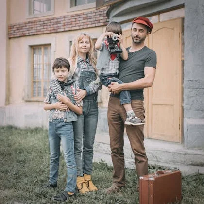 A family stands together with a suitcase and a camera, symbolizing the balance of work and family life for women.