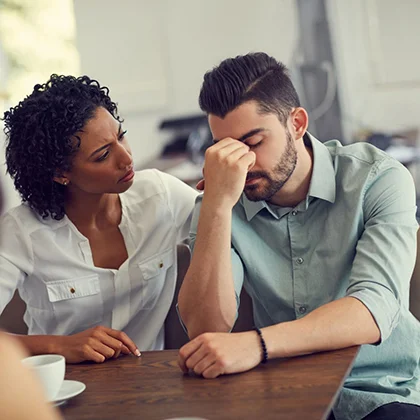 A man and woman converse over coffee at a table, representing the value of empathy and connection in professional environments.