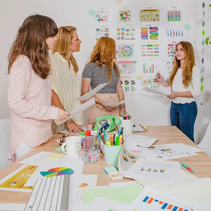 A diverse group of women gathered around a table with documents, showcasing their essential participation in the economy.