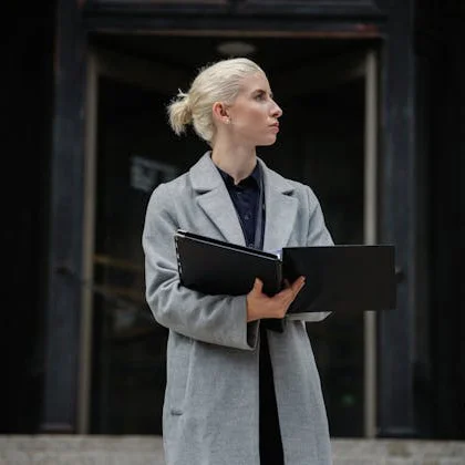 A woman dressed in a coat holds a folder, representing the significant presence of women in leadership positions